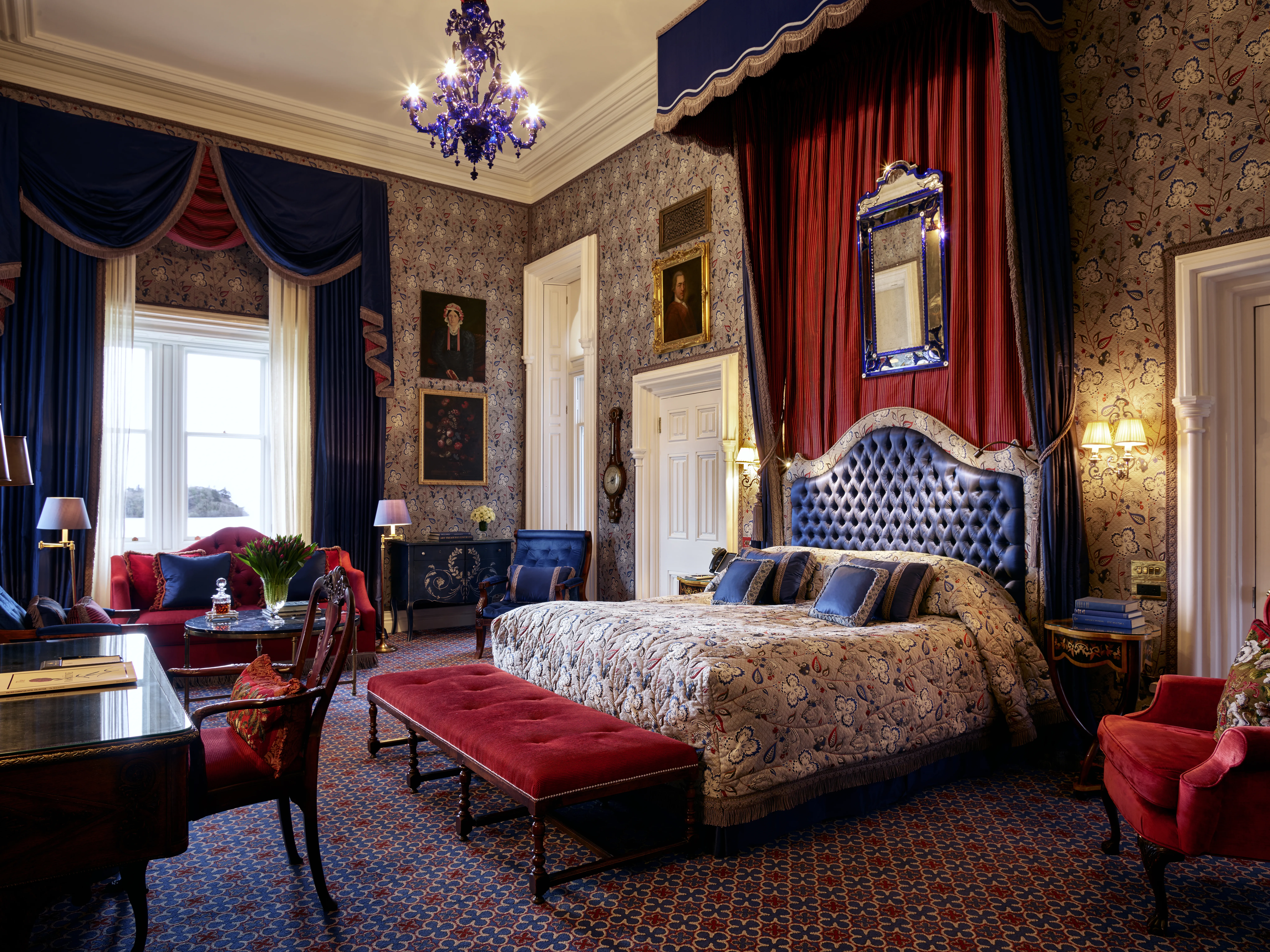 Ashford Castle castle suite with blue tufted headboard and ancestral portrait gallery walls