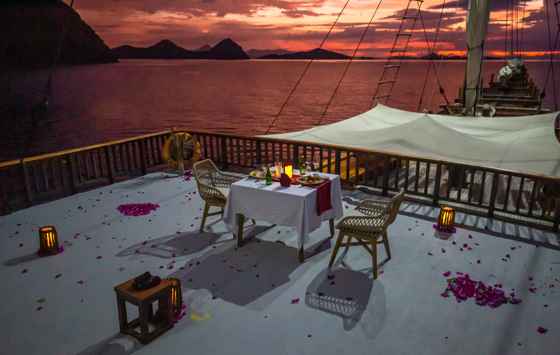 Plataran Komodo private phinisi boat dinner with rose petals and Flores Sea sunset